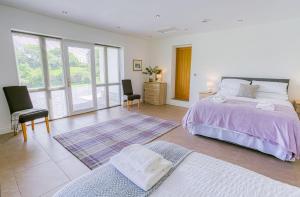 a bedroom with a large bed and two chairs at Pant yr Afallen in Llanallgo
