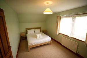 1 dormitorio con 1 cama con sábanas blancas y ventana en Woodlands House en Ballachulish
