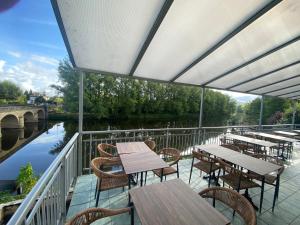 a balcony with tables and chairs next to a river at la terrasse in Larche