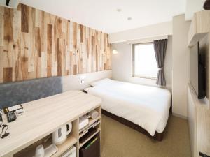 a small bedroom with a bed and a television at Super Hotel Chiba Ekimae in Chiba