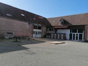 ein Backsteingebäude mit einem Parkplatz davor in der Unterkunft La ferme du Petit Chavernay in Meslay-le-Vidame