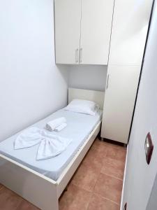 um pequeno quarto com uma cama branca e armários brancos em Cozy apartment at Sunny Hill em Tirana