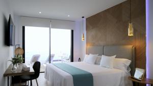 a bedroom with a white bed and a desk and a window at Villa El Buzo in Zahara de los Atunes