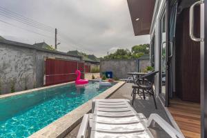 uma piscina com cadeiras e um cisne cor-de-rosa numa casa em N&D Poolvilla (1, 2, 3, 4) em Praia de Ao Nang