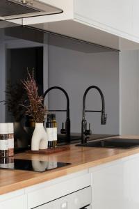 a kitchen counter with two faucets and a sink at Found at Flinders - An Iconic City Stay in Melbourne