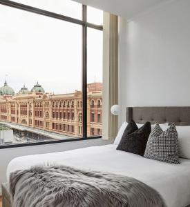 a bedroom with a large window overlooking a large building at Found at Flinders - An Iconic City Stay in Melbourne