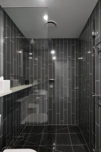 Łazienka wyłożona jest czarnymi kafelkami i dysponuje prysznicem oraz toaletą. w obiekcie 'Skyline Reflections' A Gateway to Chic City Living w Melbourne
