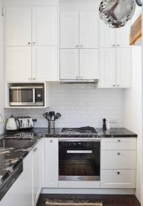 uma cozinha com armários brancos e um forno com placa de fogão em Sunny Side Up - Beachside Living on Marine Parade em Melbourne