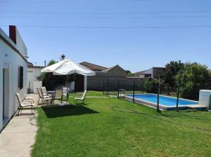 un cortile con sedie, ombrellone e piscina di Casa Rural con Piscina Verdugo a El Puerto de Santa María