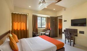 FabHotel Gargi Suites Shivajinagar في بيون: غرفة نوم بسرير ومكتب وتلفزيون