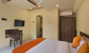 een slaapkamer met een bed, een bureau en een televisie bij FabHotel Gargi Suites Shivajinagar in Pune