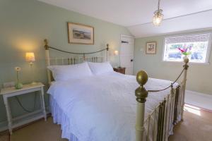 una camera da letto con un grande letto con lenzuola bianche e una finestra di Pentir a Penmon
