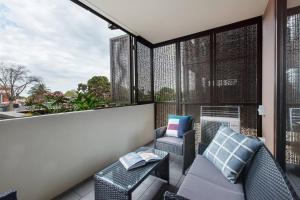 a balcony with a couch and chairs and a window at Stylish and Cosy - A Mid-Century Caulfield Retreat in Melbourne