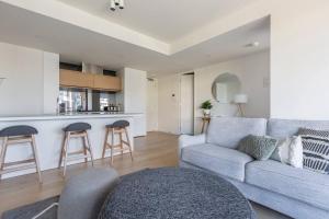 ein Wohnzimmer mit einem Sofa und einer Küche in der Unterkunft Stunning Modern Style with a Gym, Pool and Spa in Melbourne