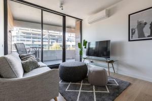 a living room with a couch and a tv at Stunning Modern Style with a Gym, Pool and Spa in Melbourne