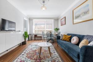 un salon avec un canapé bleu et une table dans l'établissement Rosewood Lodge - Cottage Charm off High Street, à Melbourne