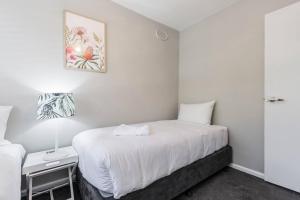 une chambre blanche avec un lit, une table et un tableau dans l'établissement Rosewood Lodge - Cottage Charm off High Street, à Melbourne