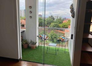 Cette chambre dispose d'un balcon avec deux chaises et une fenêtre. dans l'établissement Bonito apartamento Cocha, à Cochabamba