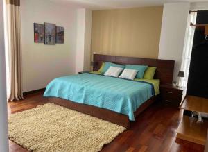 - une chambre avec un lit doté d'une couverture bleue et d'un tapis dans l'établissement Bonito apartamento Cocha, à Cochabamba