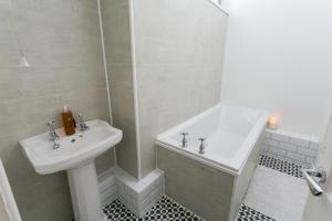 a white bathroom with a sink and a shower at Plas Cichle in Beaumaris