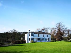 a large white house sitting on top of a lush green field at Plas Cichle in Beaumaris