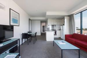 Una sala de estar con un sofá rojo y una cocina. en St Kilda Beach Sanctuary next to Albert Park, en Melbourne 12 fotos más