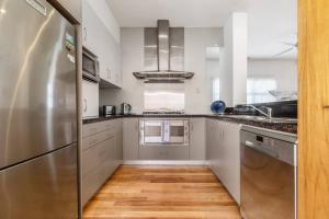 cocina con electrodomésticos de acero inoxidable y suelo de madera en The Poppy - Townhouse Chic with Country Flair, en Melbourne