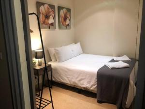 ein Schlafzimmer mit einem Bett und einem Tisch mit einer Lampe in der Unterkunft Location meets Comfort near Bourke Street Mall in Melbourne