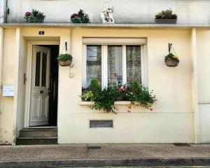 een wit huis met bloempotten op het raam bij Maison le trèfle in Chef-Boutonne