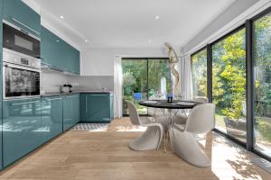 una cucina con armadi blu, tavolo e sedie di Le Jardin de Lucette - Belle maison avec jardin arboré dans Toulouse a Tolosa Altre 13 foto