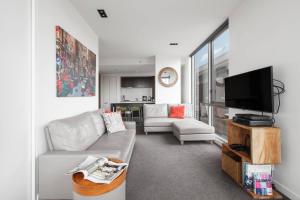 a living room with a couch and a flat screen tv at Easy Eastside - A Sunny Rooftop Pool Oasis in Melbourne
