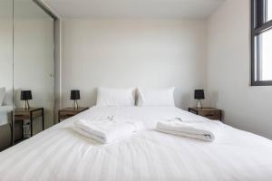 Una cama blanca con dos toallas encima. en Light-filled Stylish Living in Diverse Hawthorn, en Melbourne
