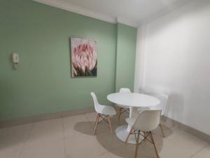 einen weißen Tisch und Stühle in einem Zimmer mit Gemälde in der Unterkunft Apartemen MTC Unit 626 in Manado