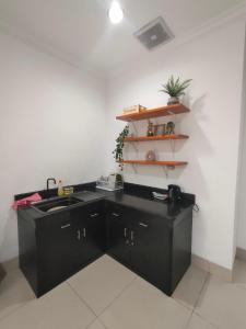 een keuken met zwarte kasten en een wastafel bij Apartemen MTC Unit 626 in Manado