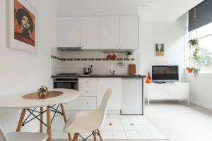 a kitchen with white cabinets and a table and chairs at Stylish Treetop Escape on Buzzing Swanston Street in Melbourne