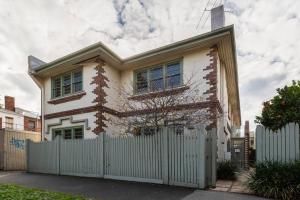 ein weißes Haus mit einem Zaun davor in der Unterkunft Port Phillip Bay Perfection in Albert Park in Melbourne