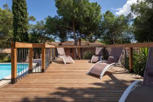 a deck with lounge chairs next to a pool at Villa Mercure in Cap d'Agde