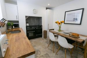 a kitchen with a wooden table and white chairs at Shell Cottage in Menai Bridge