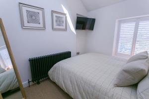 a white bedroom with a bed and a television at Shell Cottage in Menai Bridge