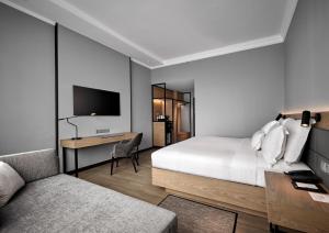 AC Hotel by Marriott Kuala Lumpur في كوالالمبور: غرفة نوم بسرير ومكتب وتلفزيون