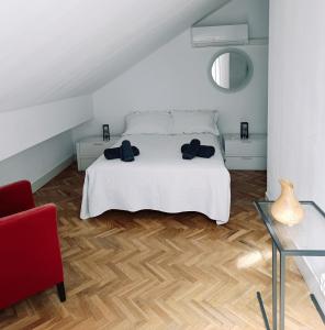 a bedroom with a white bed and a red chair at Casa de Mirtha in Madrid