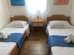 two beds in a small room with a nightstand between them at Holiday home Dumboka in Sali