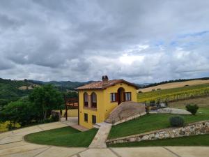 uma casa amarela num campo com um quintal em Villa Scarialetto nel Parco Naturale di Monte Cucco em Sigillo