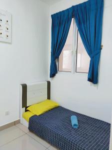 a bedroom with a bed and a window with blue curtains at Palmyra Residence in Kajang