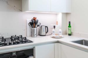 a white kitchen with a stove and a sink at Stylish Kings Cross Flat in London