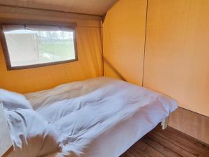 Bett in einem kleinen Zimmer mit Fenster in der Unterkunft Luxury glamping with private bathroom near the Frisian waters in De Veenhoop