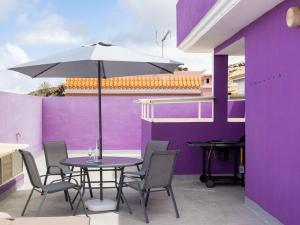 a table and chairs with an umbrella on a purple wall at Live Icod Buen Paso in Icod de los Vinos