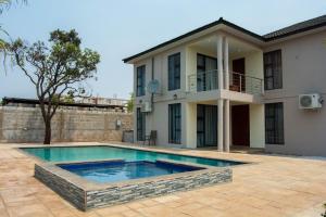 une villa avec une piscine en face d'une maison dans l'établissement Ista Villa, à Lusaka