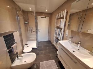 ein Badezimmer mit zwei Waschbecken, einer Dusche und einem WC in der Unterkunft Ferienwohnung Moselhöhe in Perl