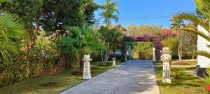 una pasarela a través de un jardín con palmeras y plantas en Villa Lilly Sea View Pool Villa, en Umeanyar